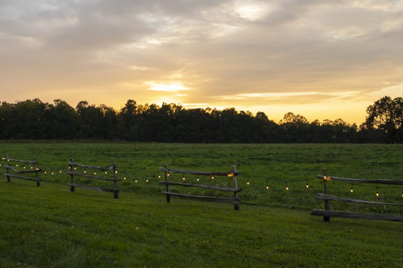 String lights adorn a fence along field