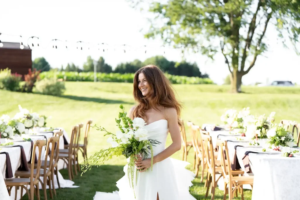 Bride holding a bouquet beside an outdoor wedding reception in the garden at Fermanagh Farms